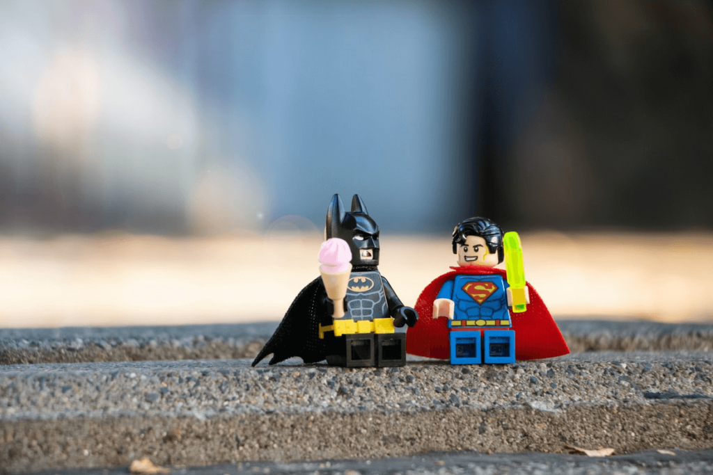 Figurki Lego Batmana i Supermana siedzą na bruku 